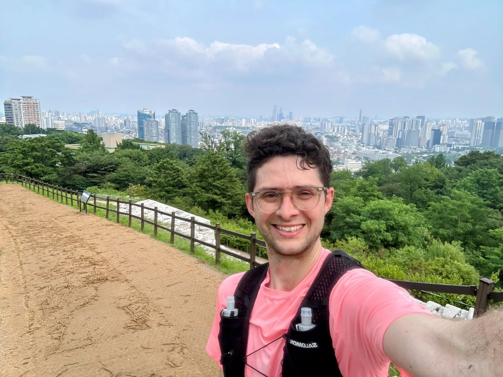 Quintin mid-run on the Seoul City Wall trail on Namsan, running vest on, the Seoul skyline behind him