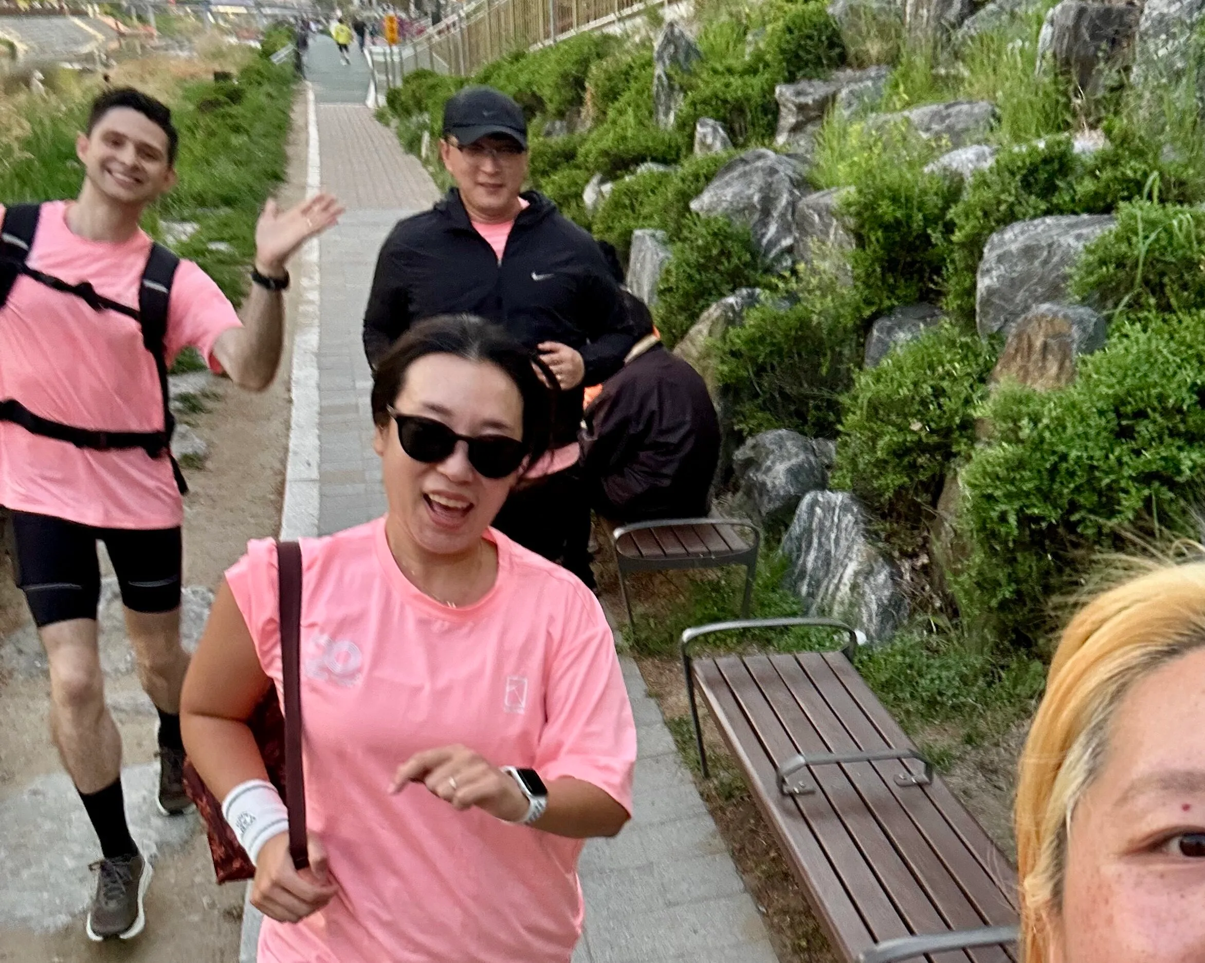 Quintin and a small group running a landscaped park path in Seoul, runners smiling mid-stride.
