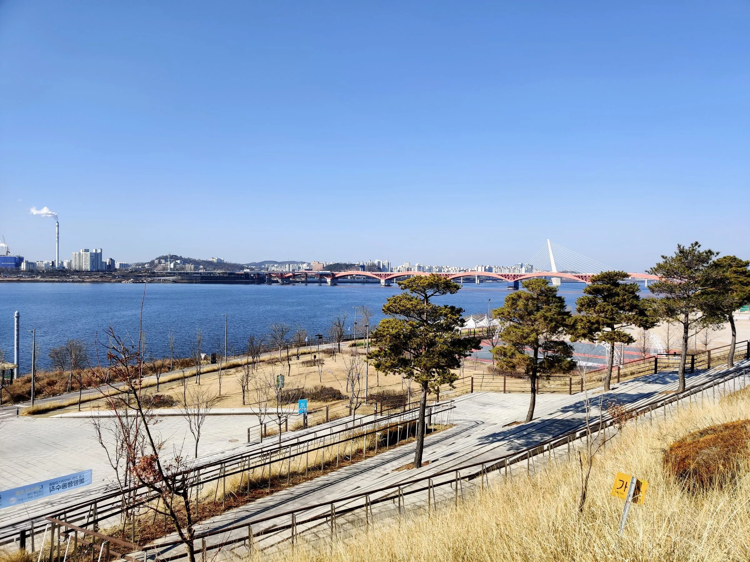 The Han River walking and running path in Mapo on a clear winter morning, lined with bare trees.