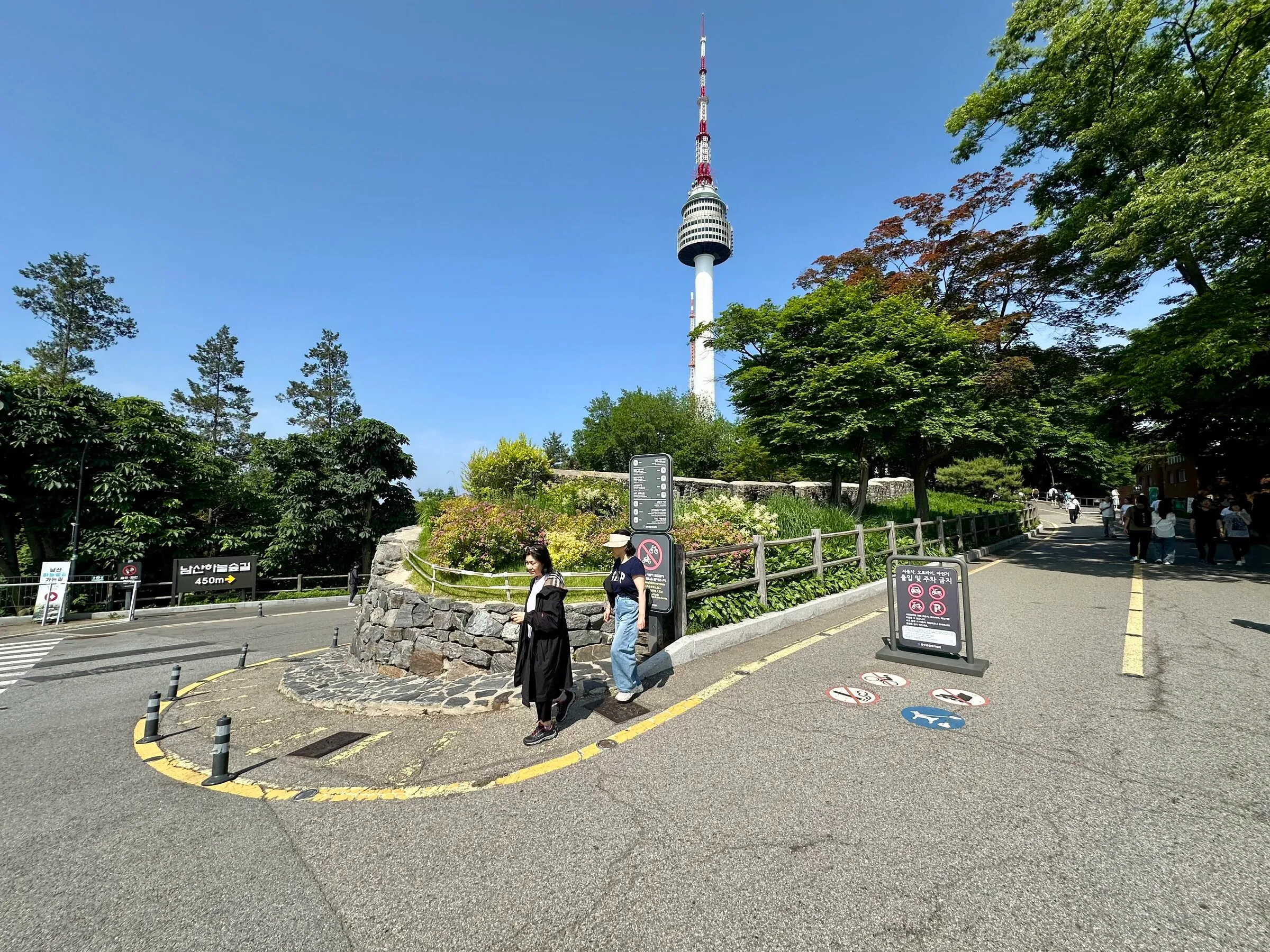 The turning point near the Namsan summit beneath N Seoul Tower, a small stone roundabout with directional signage and the tower above.
