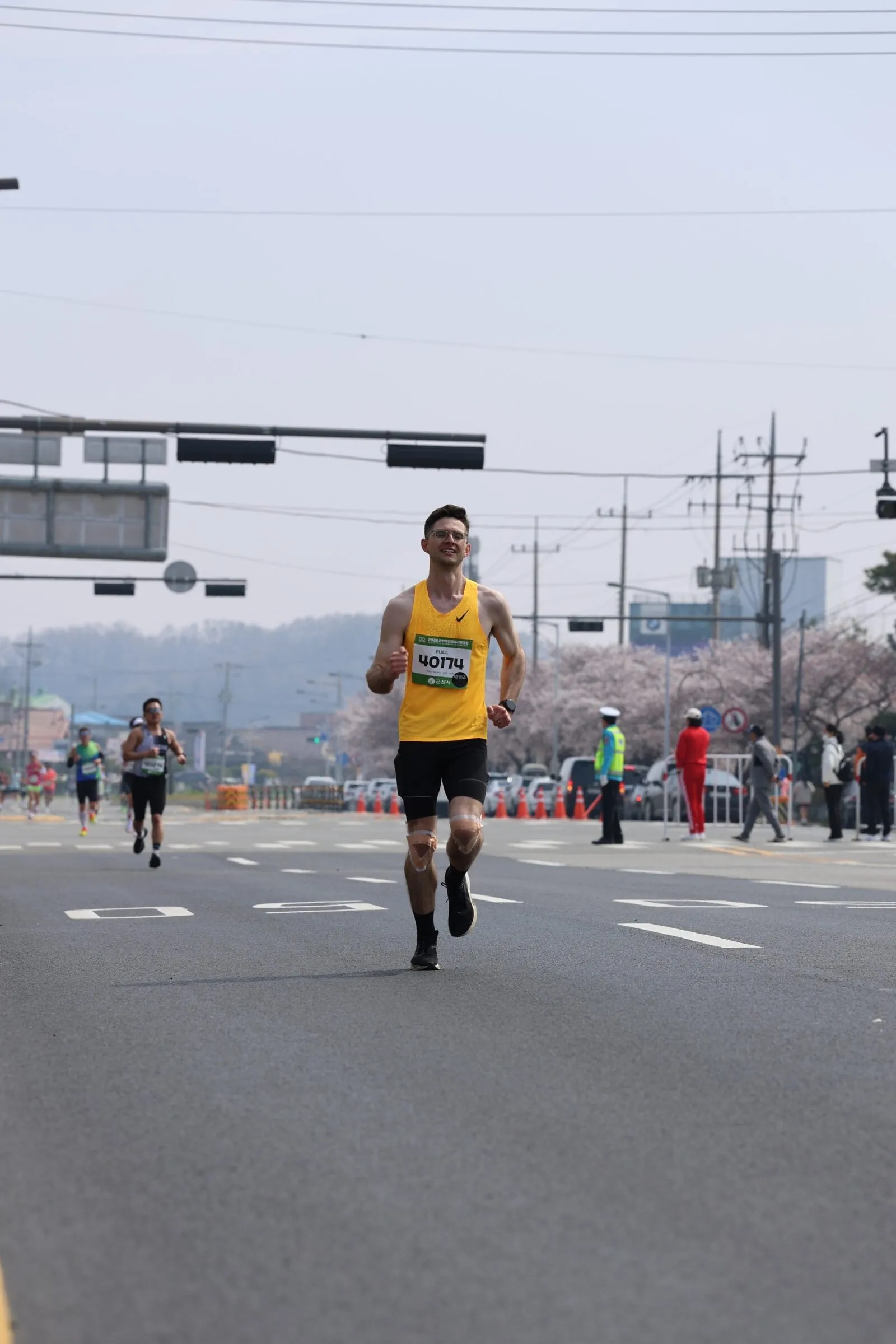 Quintin running a cherry-blossom-lined road at a spring marathon in Korea.