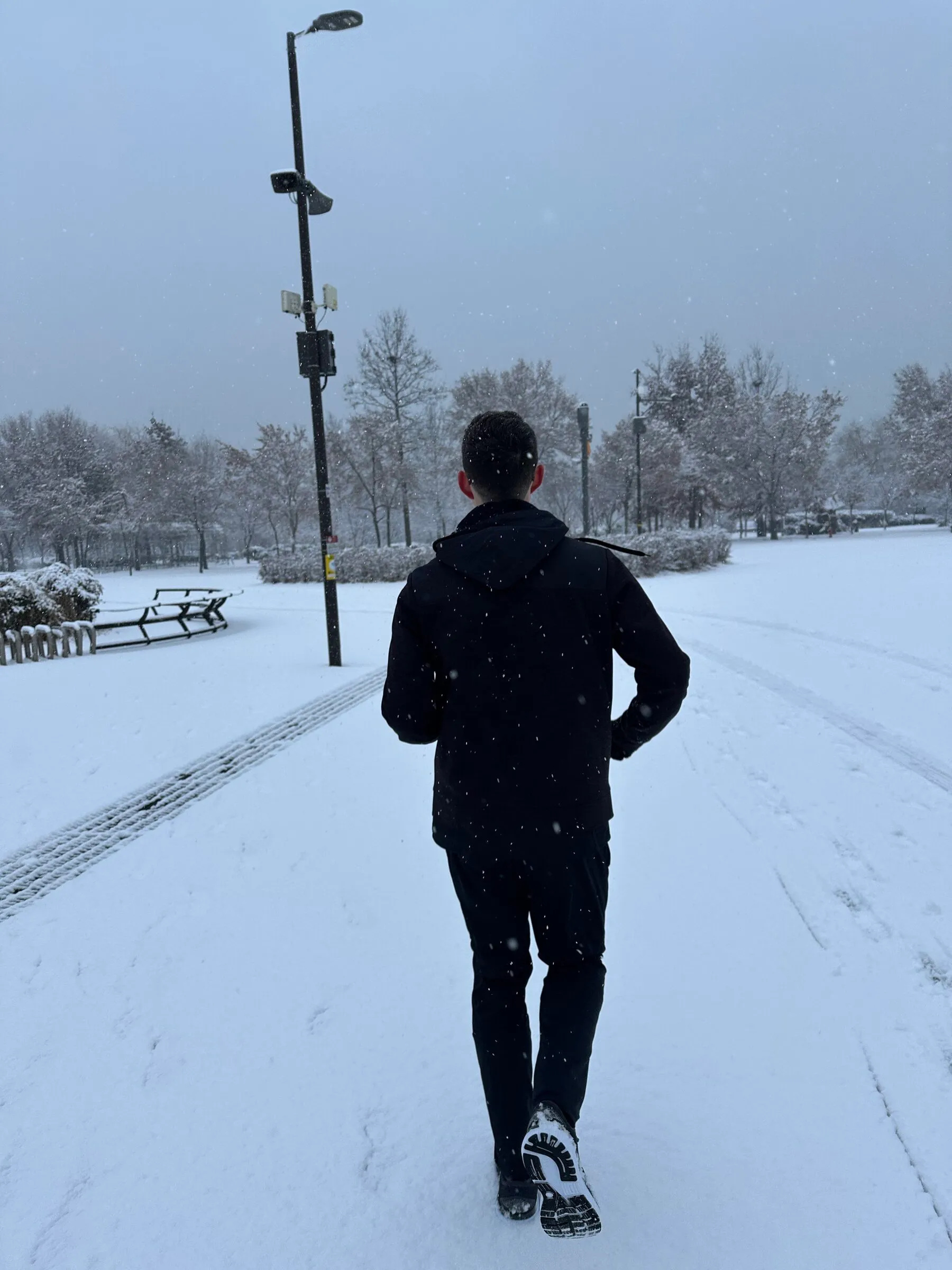 A runner heading down a snow-covered path on a winter morning in Seoul.