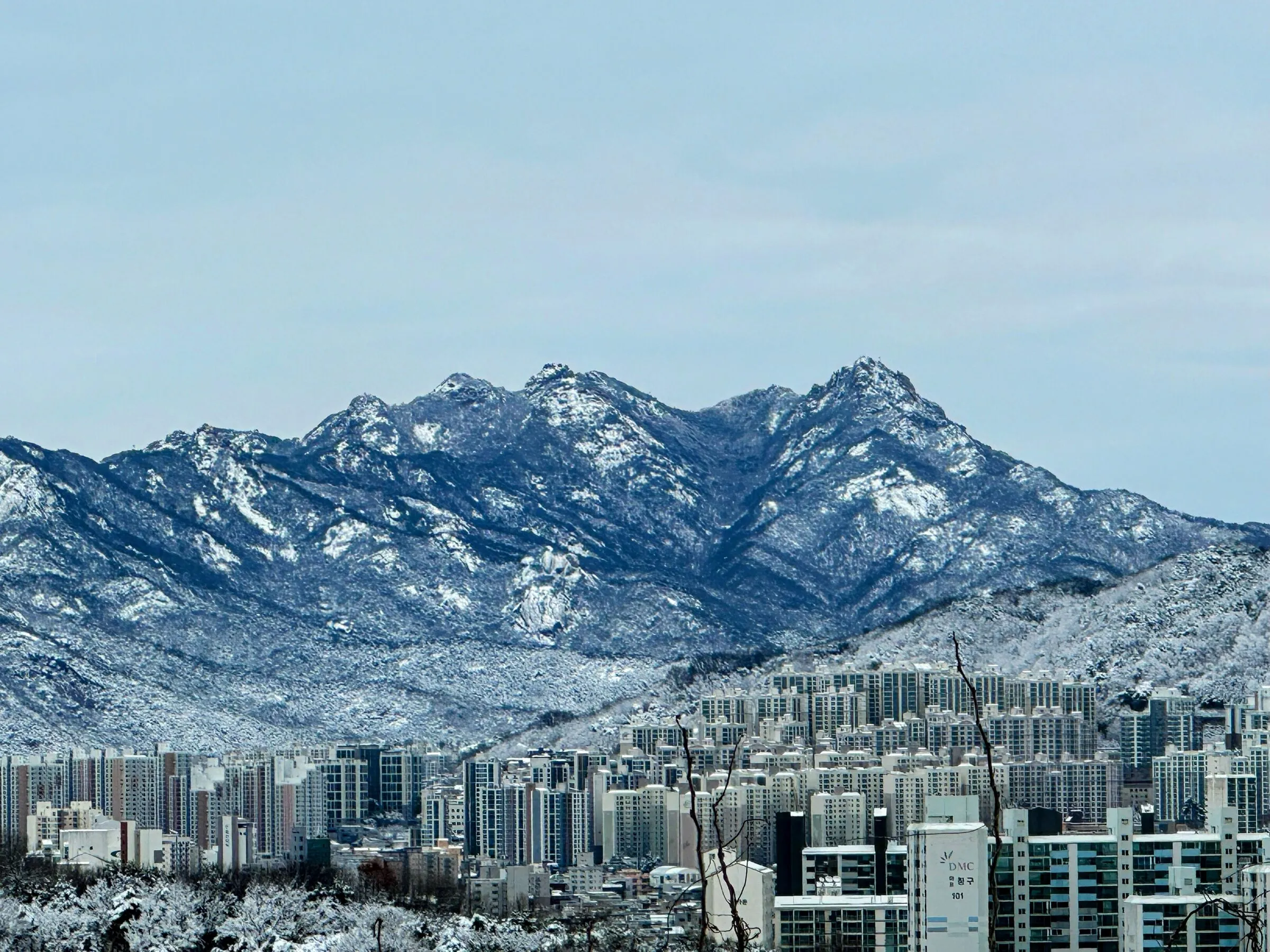 서울 아파트 단지 뒤로 솟은 눈 덮인 산.