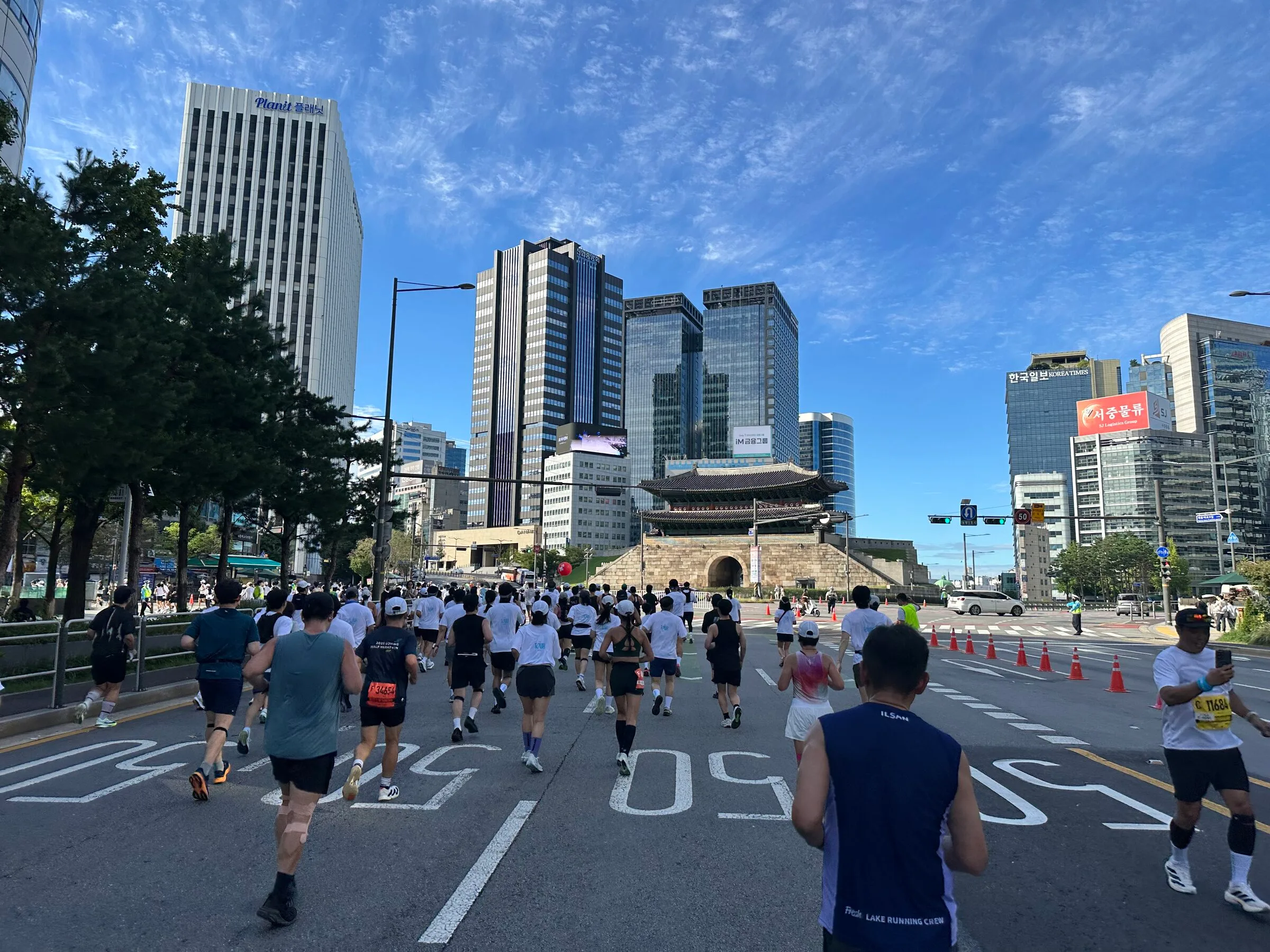 Runners on the closed road in front of Sungnyemun, the great south gate, under a bright blue morning sky.