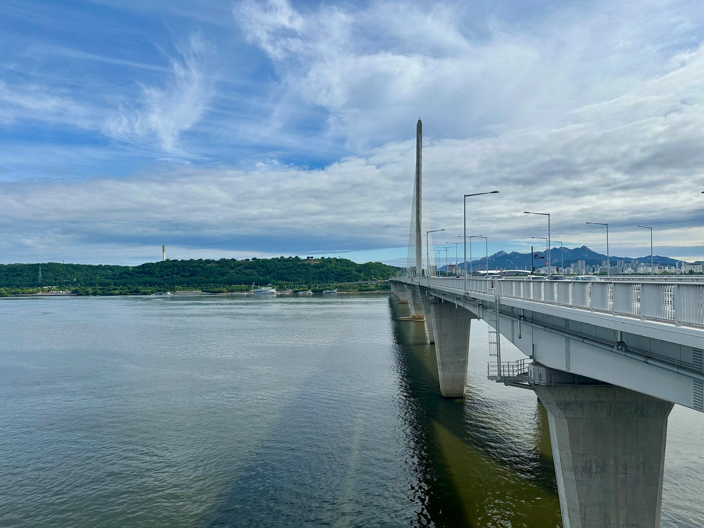 The white cable-stayed World Cup Bridge sweeping across the Han River toward the granite peaks of Bukhansan.
